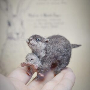 This needle felted otter holds a tiny baby, which can be displayed separately. Wire in the limbs allows gentle pose changes — a perfect river scene in miniature.