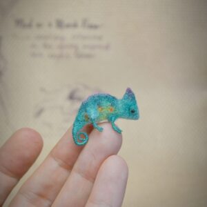 This 1.5–2 cm felted chameleon is handmade from wool with curled tail and wire legs. A colorful micro reptile for exotic collectors and miniature jungle scenes.