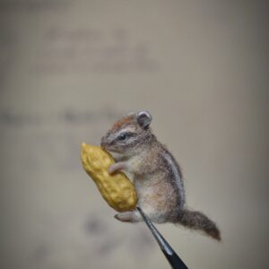 This tiny 2 cm needle felted chipmunk holds a removable peanut! A sweet forest creature made from wool, perfect for miniature scenes or handmade gift giving