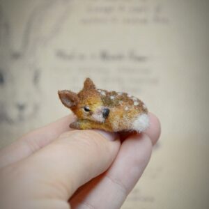 This tiny curled-up fawn is handmade from wool in a peaceful sleeping pose. A soft woodland miniature for forest scenes, winter decor, or animal lovers.
