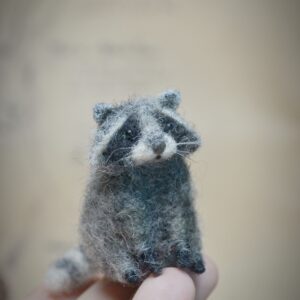Needle felted raccoon miniature in a sitting pose. Handmade wool figurine, perfect for dollhouses, woodland dioramas, and collectors.